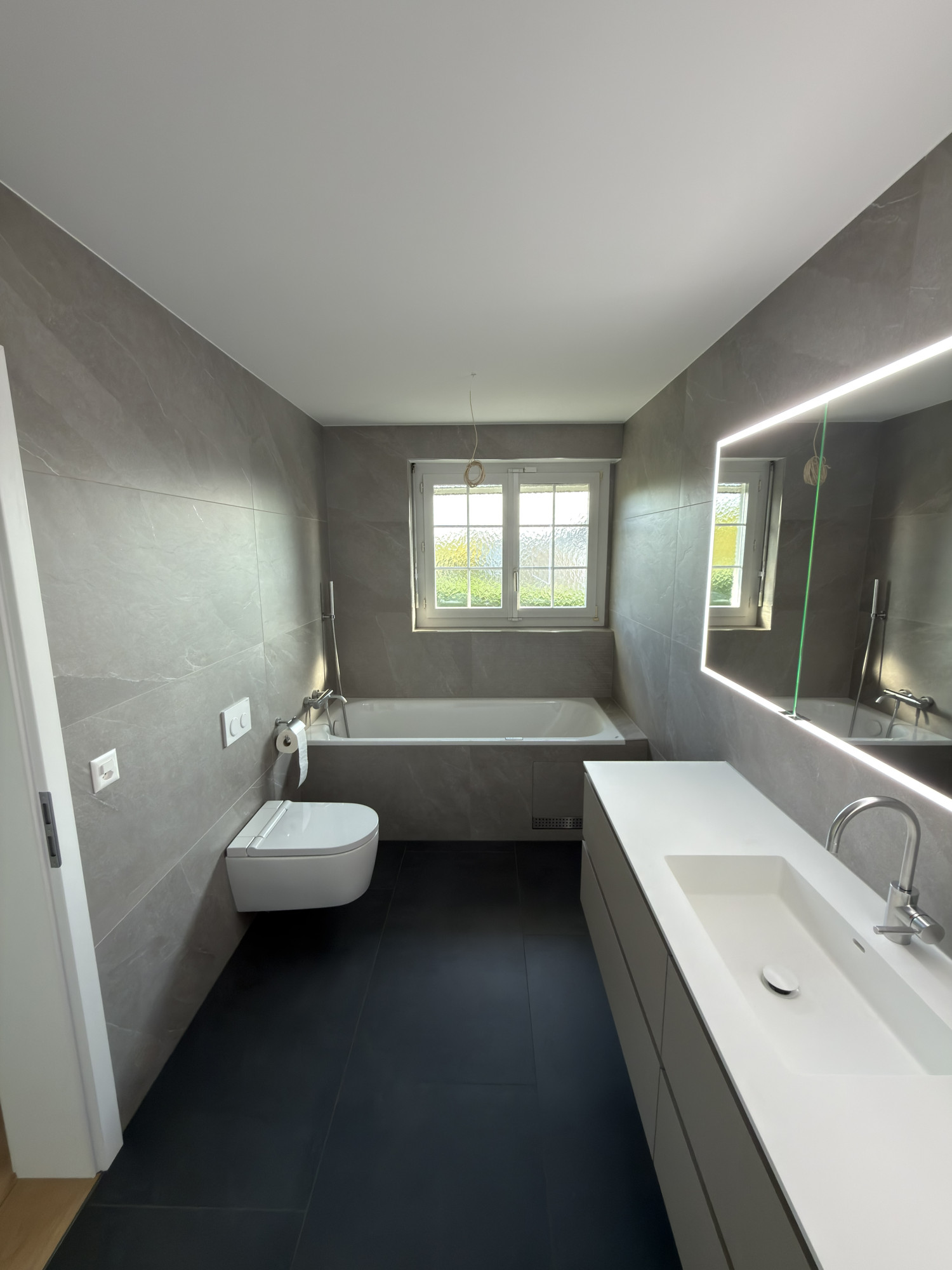 Plattenleger Bern Badezimmer mit Badewanne und LED Spiegel