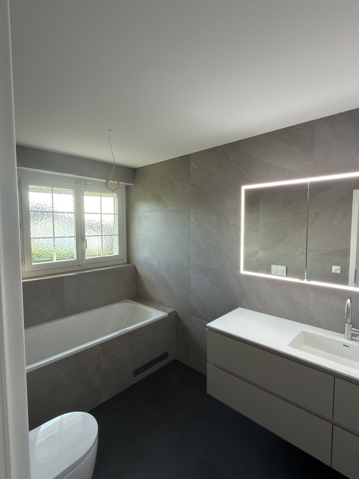 Modernes Badezimmer Renovation Bern graue Wand- und Bodenplatten